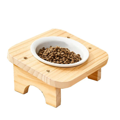 Gamelle chat inclinée 1 bol céramique blanche avec croquettes sur support bois naturel compact, fond blanc